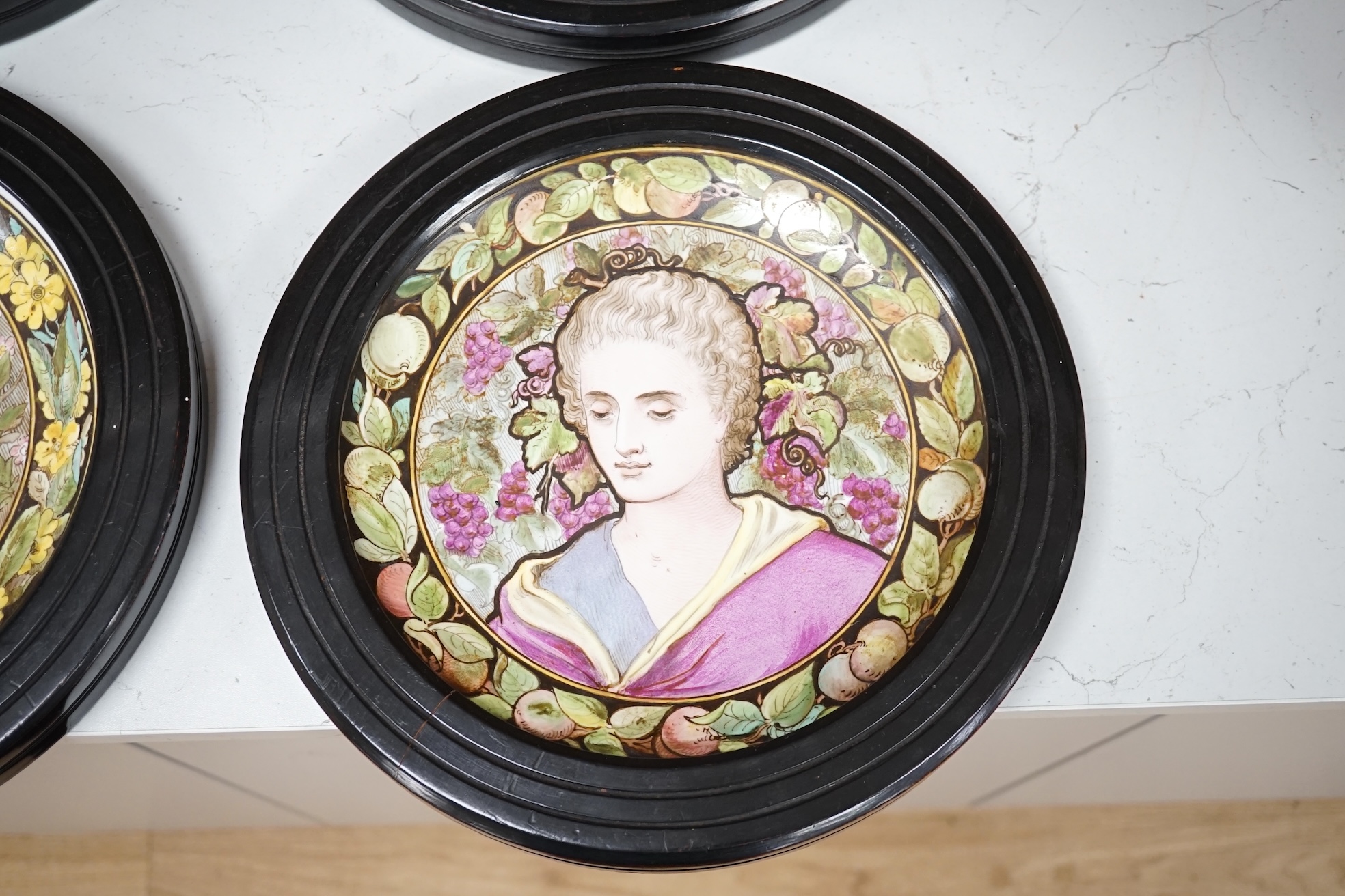 A set of four Copeland Spode Aesthetic period, outside decorated four seasons portrait plates, circa 1880, housed in ebonised wood frames, overall 31cm in diameter. Condition - fair, three frames cracked